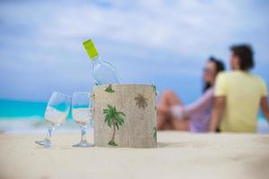 fles van wit wijn en twee bril Aan de exotisch zanderig strand foto