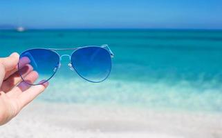 dichtbij omhoog van kleurrijk blauw zonnebril Aan tropisch strand foto