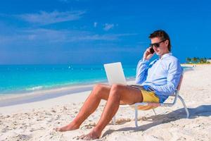 jong zakenman gebruik makend van laptop Aan tropisch strand foto