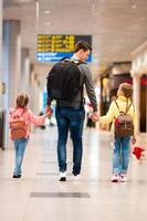 gelukkig familie met twee kinderen in luchthaven hebben pret aan het wachten voor instappen foto