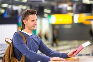 mooi Mens met paspoorten en instappen passeert Bij de voorkant bureau Bij luchthaven foto