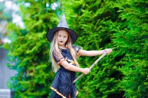 aanbiddelijk weinig meisje vervelend heks kostuum met bezem Aan halloween buitenshuis foto