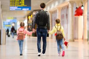 gelukkig familie met twee kinderen in luchthaven hebben pret aan het wachten voor instappen foto