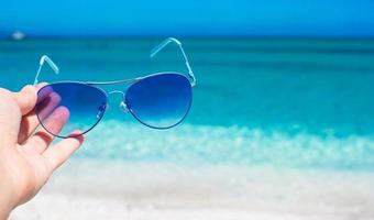 dichtbij omhoog van kleurrijk blauw zonnebril Aan tropisch strand foto