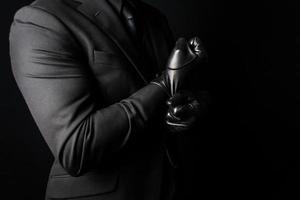 portret van sterk Mens in donker pak trekken Aan zwart leer handschoenen. concept van maffia huurmoordenaar of heer Sluipmoordenaar foto