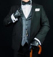 portret van heer in donker pak en leer handschoenen Holding paraplu. wijnoogst stijl en retro mode van elegant zakenman. foto