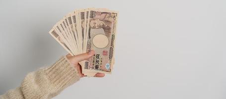 vrouw hand- Holding Japans yen bankbiljet stapel. duizend yen geld. Japan contant geld, belasting, recessie economie, inflatie, investering, financiën en boodschappen doen betaling concepten foto