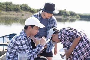 jong Aziatisch jongen houdt transparant buis welke heeft voorbeeld water binnen naar Doen de experiment en ph niveau meting net zo zijn school- project werk met zijn vrienden achter Bij de rivier- waar hij leefde. foto