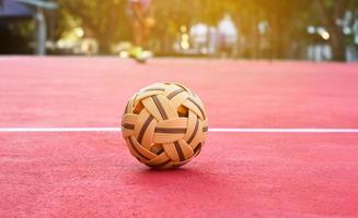 sepak takraw bal Aan rood verdieping van buitenshuis rechtbank, wazig achtergrond, recreatief werkzaamheid en buitenshuis sport- in zuidoosten Aziatisch landen concept. foto