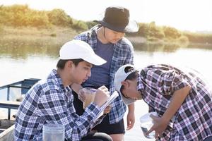 jong Aziatisch jongen houdt transparant buis welke heeft voorbeeld water binnen naar Doen de experiment en ph niveau meting net zo zijn school- project werk met zijn vrienden achter Bij de rivier- waar hij leefde. foto