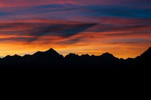 donker silhouet van bergen en zonsondergang. berg pieken dolomieten. brent, Italië foto