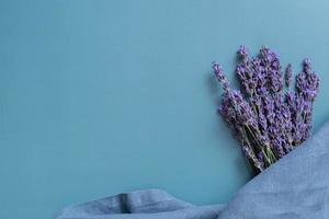 lavendel bloemen en keuken nepkin Aan gekleurde achtergrond top visie. kopiëren ruimte. foto