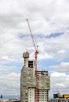 hijsen kranen werken gebouw bouw Aan helder blauw lucht en groot wolk achtergrond. foto