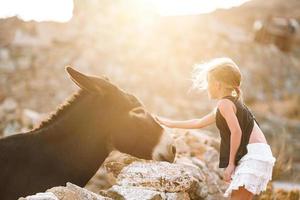 weinig meisje met ezel Aan de eiland van Mykonos foto