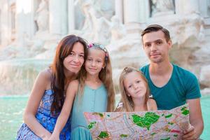 portret van familie met toeristisch kaart in de buurt fontana di trevi, Rome, Italië. gelukkig ouders en kinderen genieten Italiaans vakantie vakantie in Europa. foto