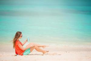 mooi jong vrouw Holding een zonnecreme aan het liegen Aan tropisch strand foto