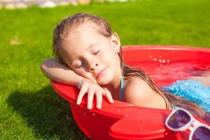 portret van ontspannen schattig klein meisje genieten van haar vakantie in een klein zwembad buiten foto