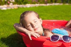 portret van ontspannen schattig klein meisje genieten van haar vakantie in een klein zwembad buiten foto