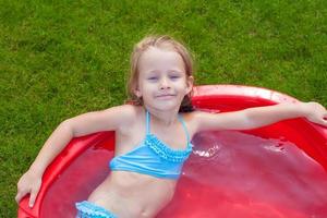 schattig weinig meisje genieten van haar vakantie in de zwembad buitenshuis foto
