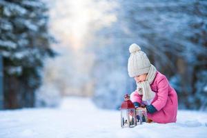 aanbiddelijk weinig meisje met latern in bevroren Woud Aan Kerstmis Bij winter dag foto