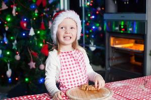 portret van aanbiddelijk weinig meisje in de keuken bakken peperkoek foto