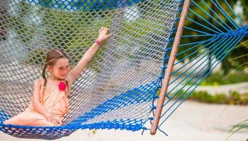 schattig klein meisje dat in een hangmat op het strand zwaait foto