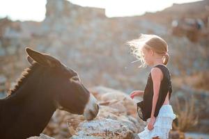 weinig aanbiddelijk meisje met wild ezel Aan Grieks eiland buitenshuis foto