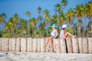 weinig meisjes hebben pret Bij tropisch strand gedurende zomer vakantie spelen samen foto