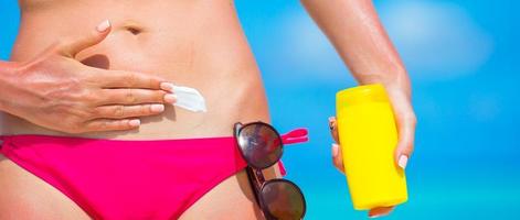 detailopname vrouw hand- toepassen met zonnescherm Aan wit strand foto