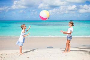 weinig aanbiddelijk meisjes spelen met bal Aan de strand. kinderen hebben pret Aan de kust foto