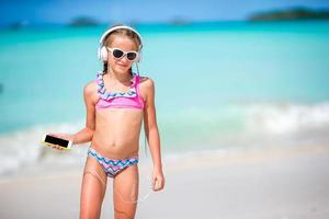 weinig meisje met hoofdtelefoons Aan de strand foto