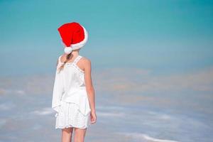 schattig klein meisje in kerstmuts op tropisch strand foto