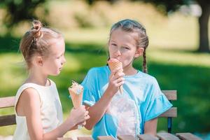 weinig meisjes aan het eten ijsje buitenshuis Bij zomer in buitenshuis cafe foto