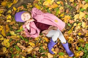 weinig gelukkig meisje in herfst park Aan zonnig vallen dag foto