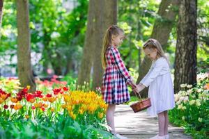 weinig aanbiddelijk meisjes wandelen in weelderig tuin van tulpen foto