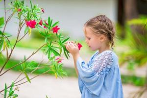 weinig aanbiddelijk meisje ruiken kleurrijk bloemen buitenshuis foto