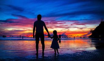 vader en dochter silhouetten in zonsondergang Bij de strand Aan Boracay foto