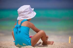 terug visie van weinig meisje in mooi hoor zwempak spelen Aan zanderig strand foto