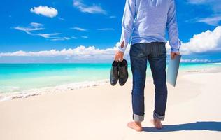 jong Mens met laptop gedurende tropisch strand vakantie foto