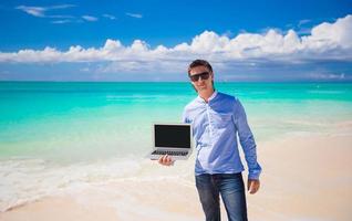 jong Mens met laptop gedurende strand vakantie foto