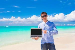 jong Mens met laptop gedurende strand vakantie foto