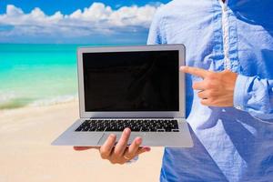 jong Mens met laptop gedurende strand vakantie foto