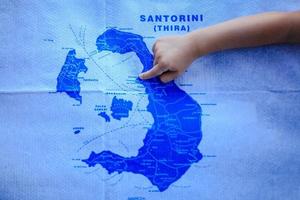 meisje points vinger Bij de kaart van eiland van santorini, Griekenland foto