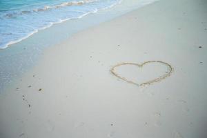 hart geschilderd in wit zand Aan een tropisch strand foto