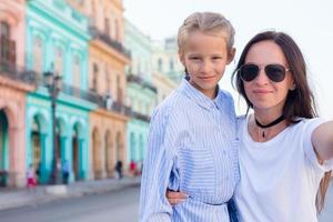 familie van mam en weinig meisje nemen selfie in populair Oppervlakte in oud havanna, Cuba. weinig kind en jong moeder buitenshuis Aan een straat van Havana foto