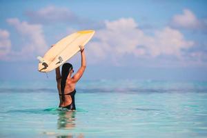 mooi surfer vrouw klaar naar surfing in turkoois zee, Aan staan omhoog peddelen bord Bij exotisch vakantie foto