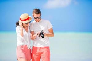 gelukkig paar nemen een selfie foto Aan wit strand. twee volwassenen genieten van hun vakantie Aan tropisch exotisch strand