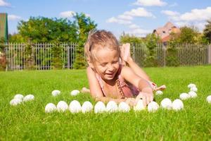 weinig aanbiddelijk meisje spelen met wit Pasen eieren in de werf foto