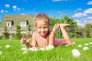 weinig aanbiddelijk meisje spelen met wit Pasen eieren in de werf foto