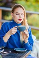 vallen concept - mooi vrouw drinken koffie in herfst park onder vallen gebladerte foto